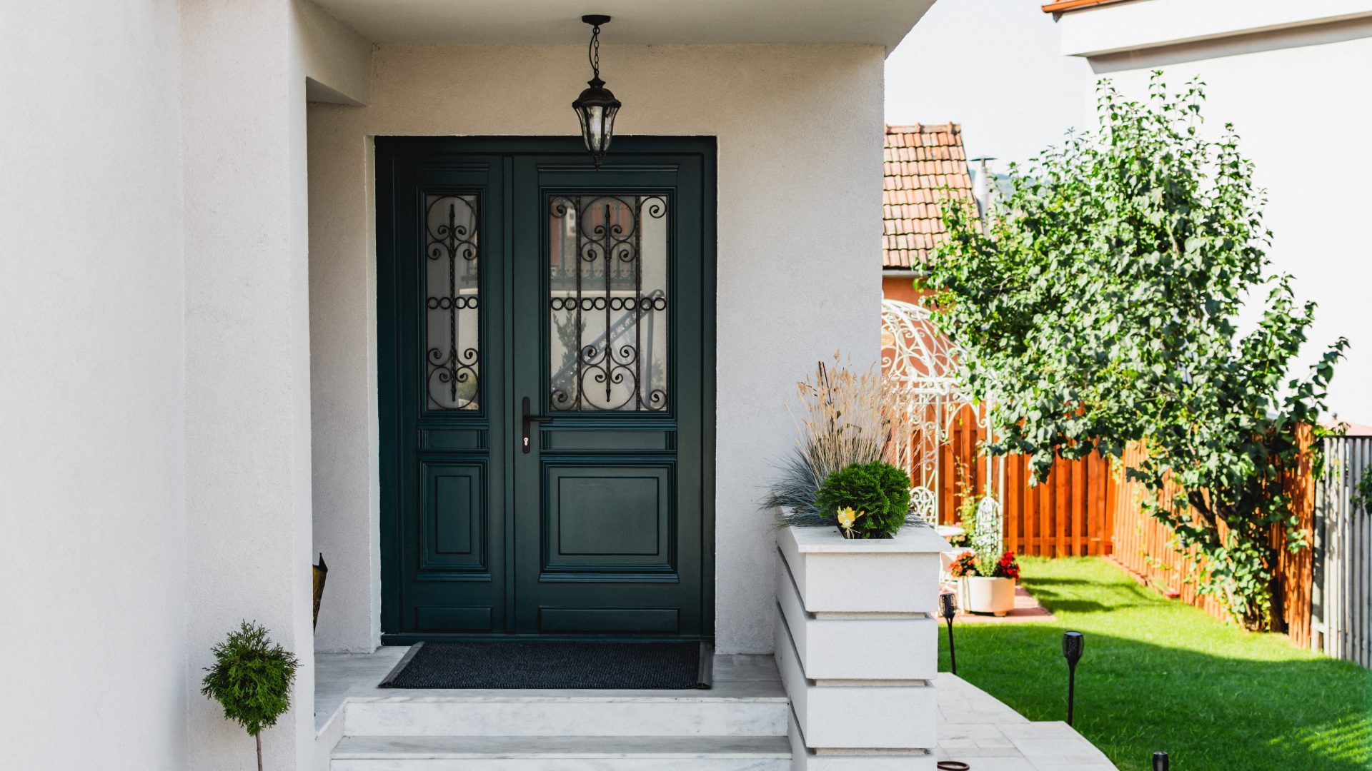 A deep green entry door with ornate decorative glass and sidelight