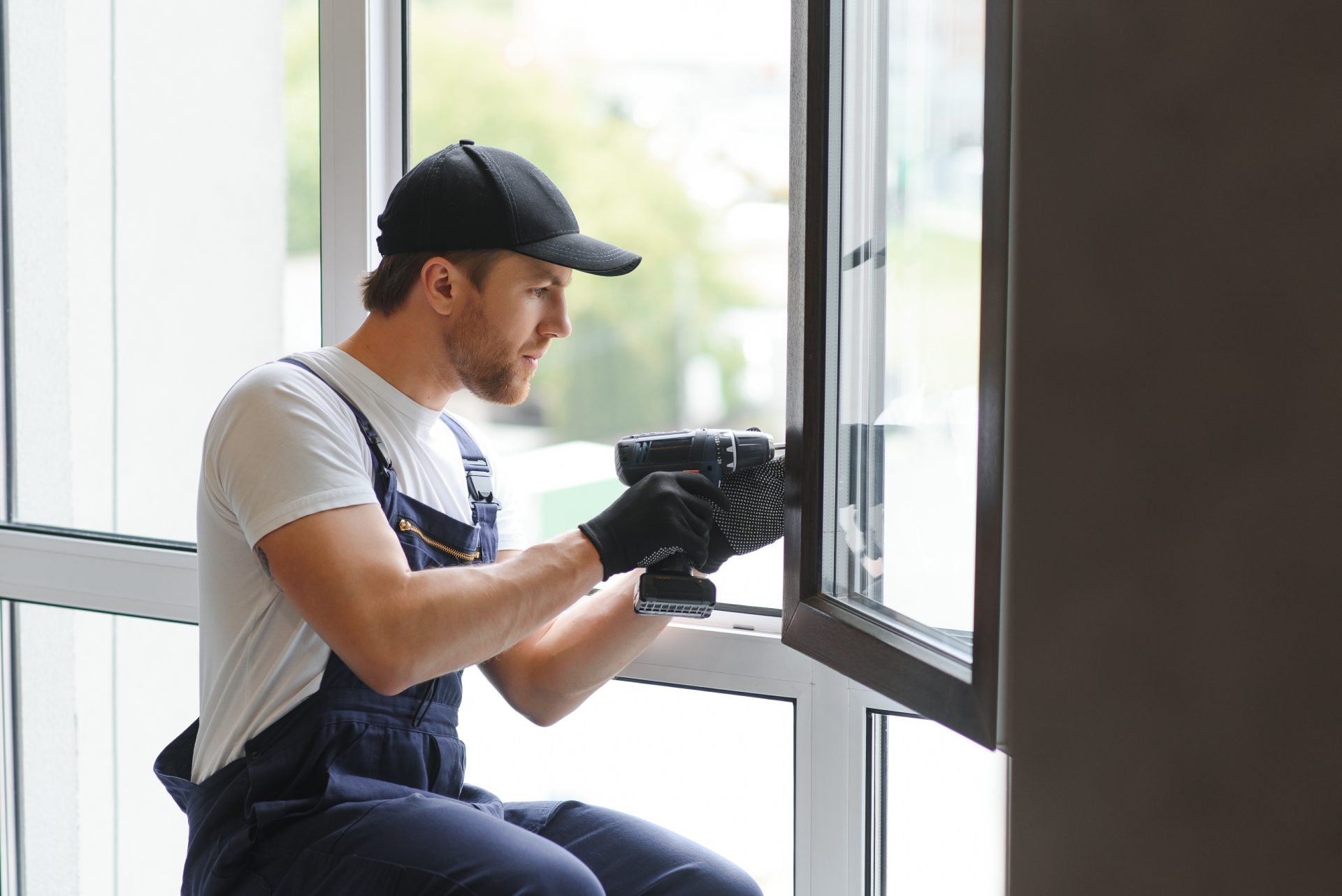Worker kneeling with drill to mount new window