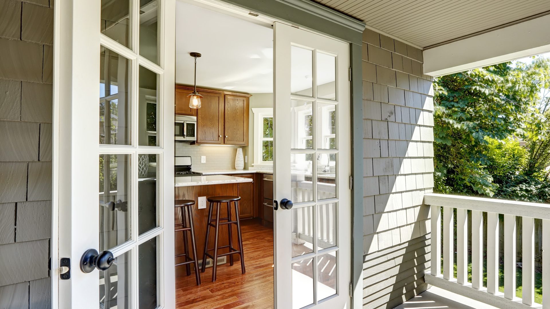 Close, angled view of an open French door on a shaded suburban back porch