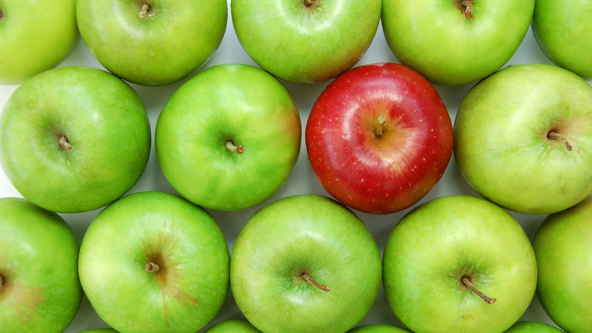 One red apple among many green apples.