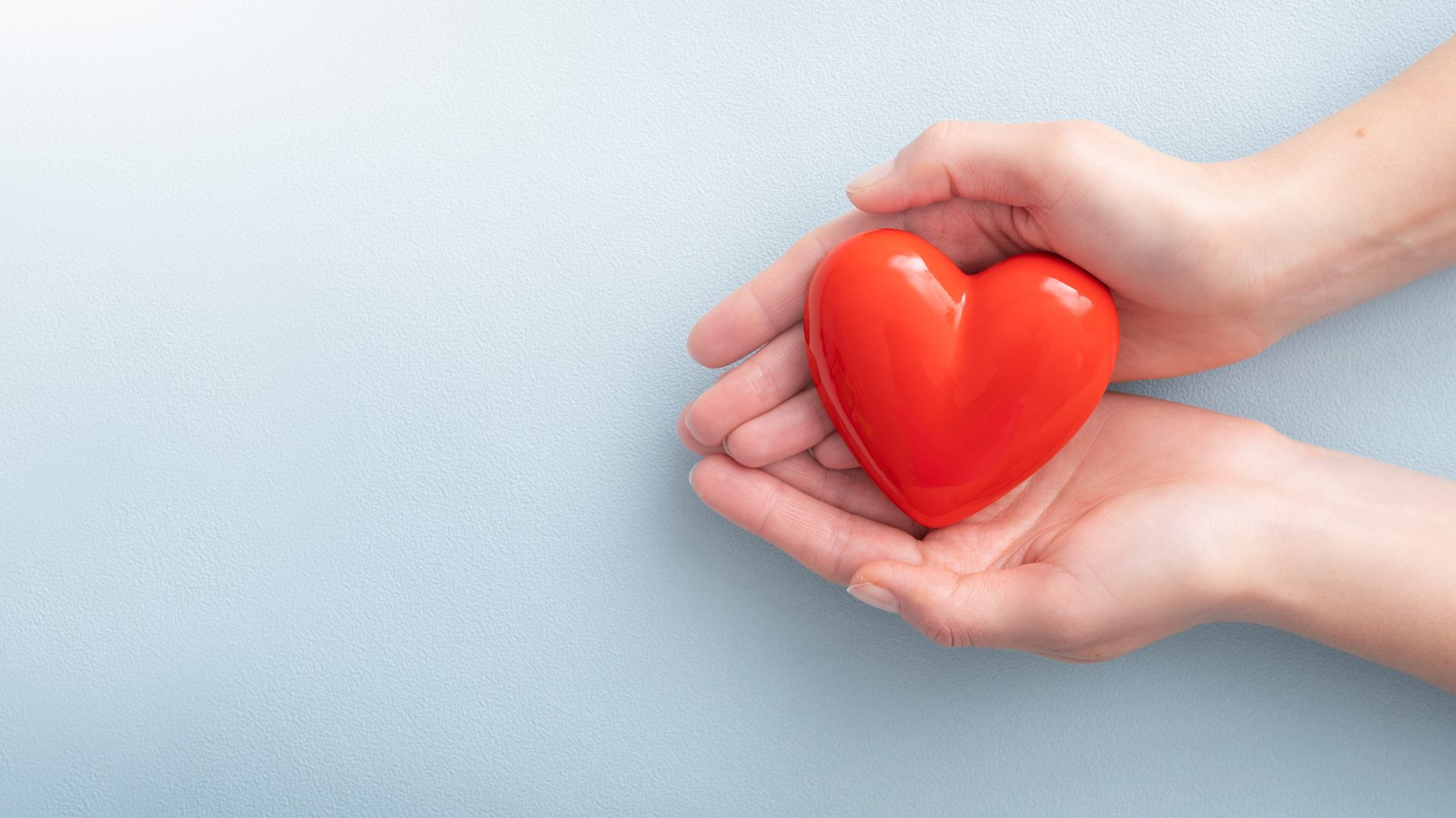 A woman’s hands holding a red heart