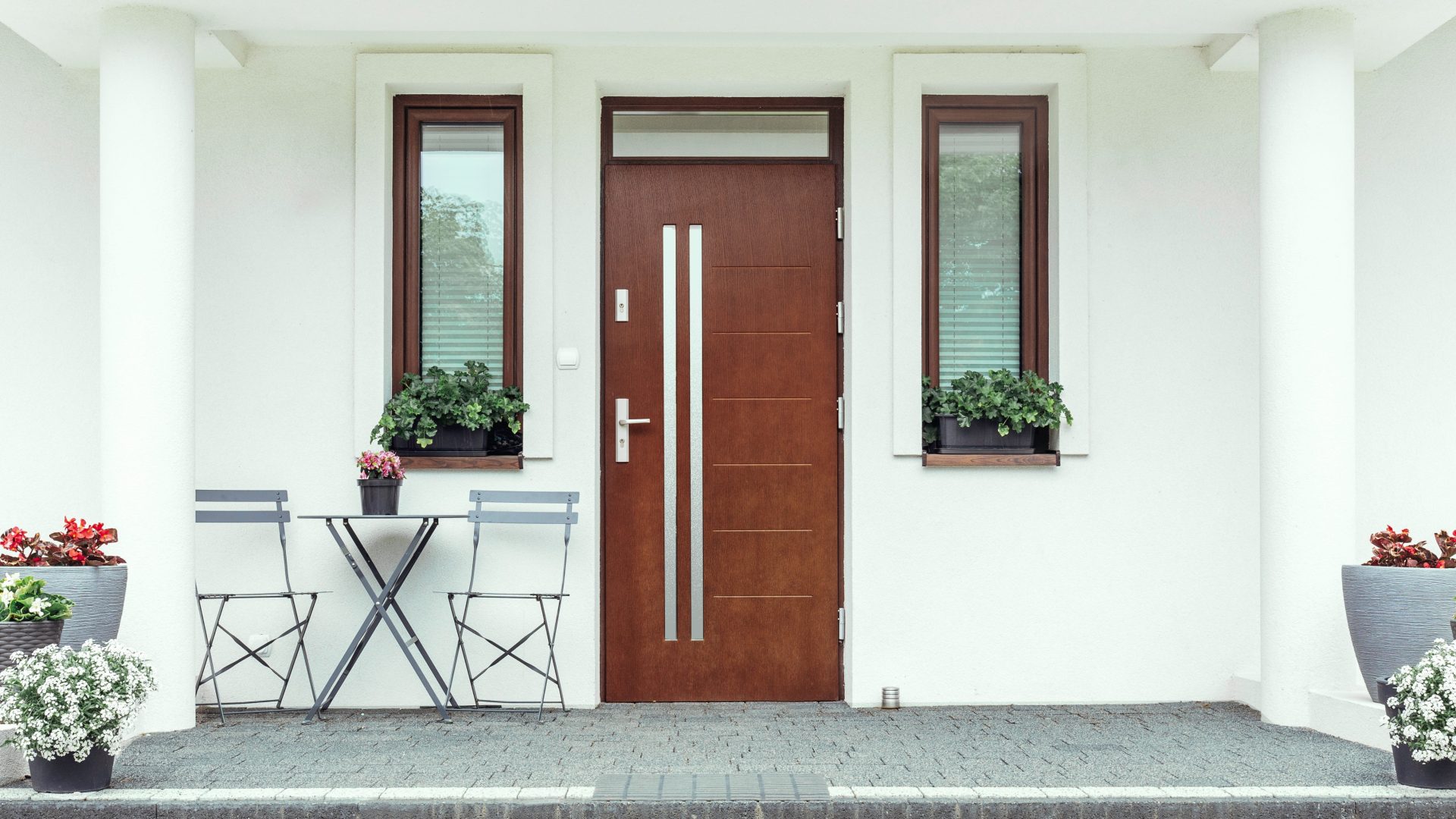 Frontal view of a modern front door with a transom installed a white house with porch columns