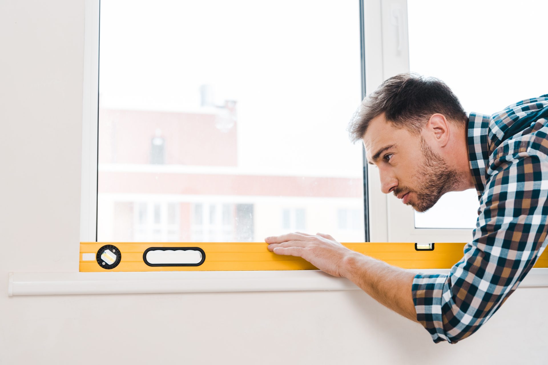 An Alberta area homeowner uses a level to ensure his windows are properly installed