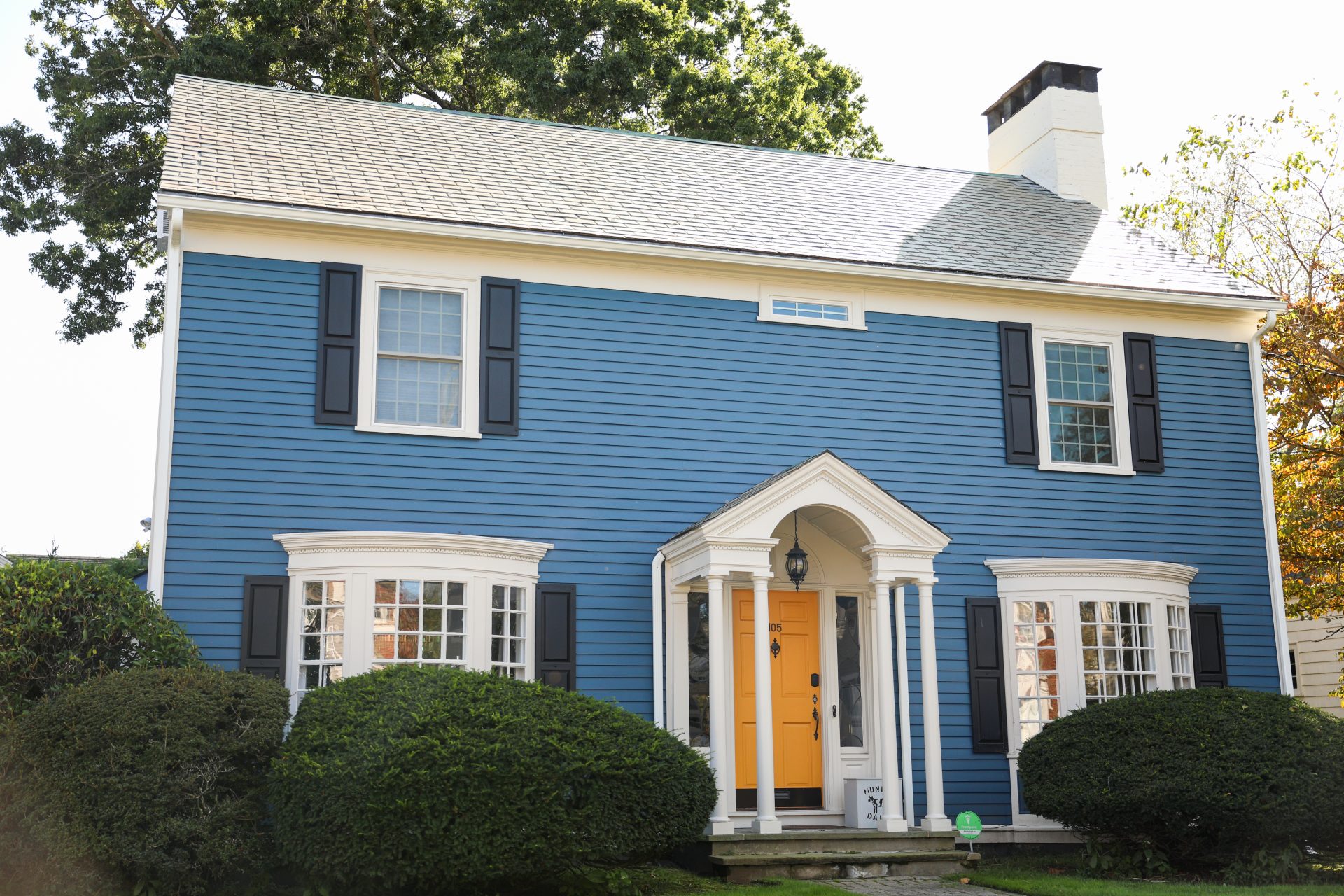 Two-story colonial style blue house with a yellow door