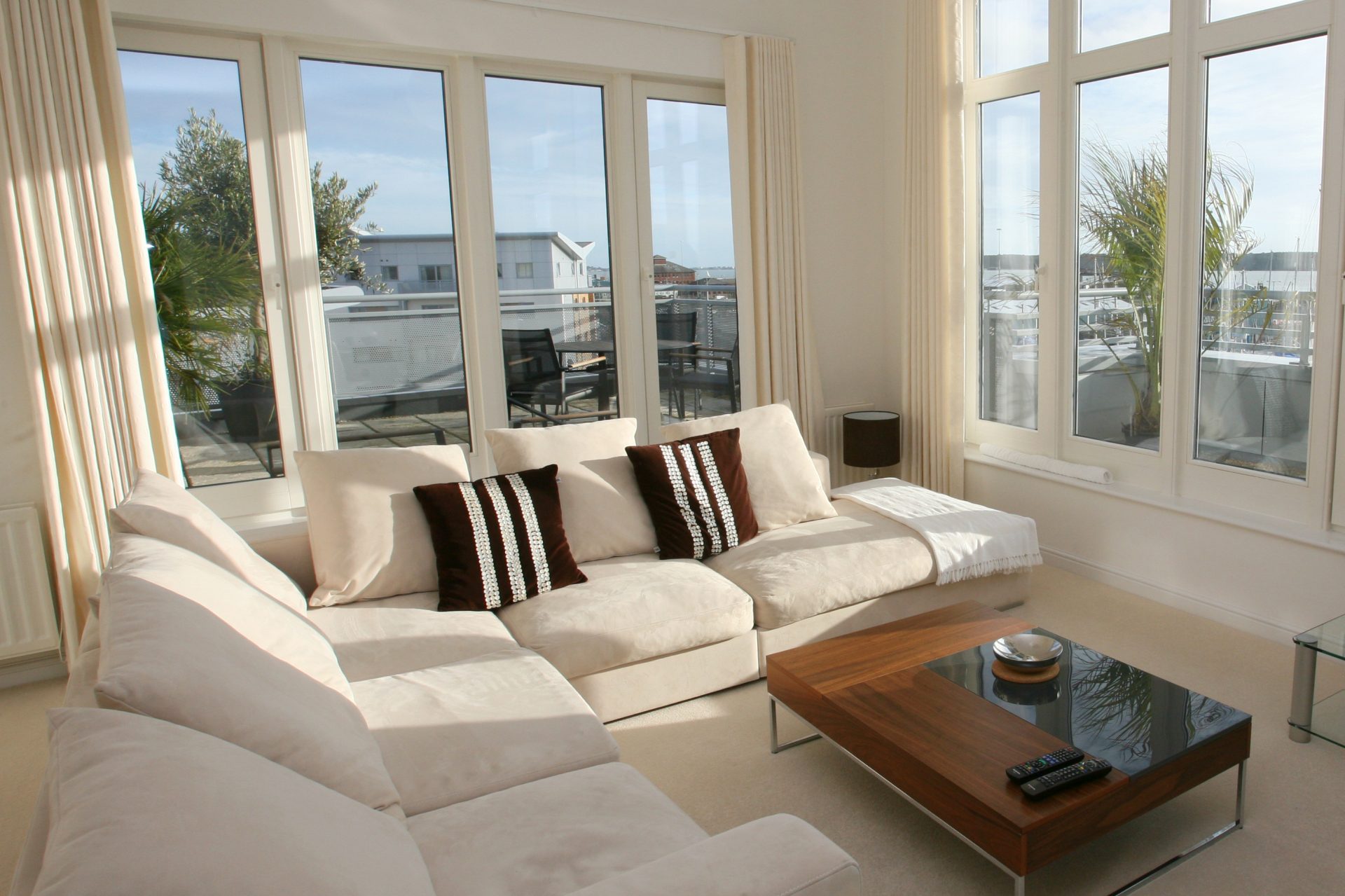 Large windows in a modern living room with a white couch and wood table