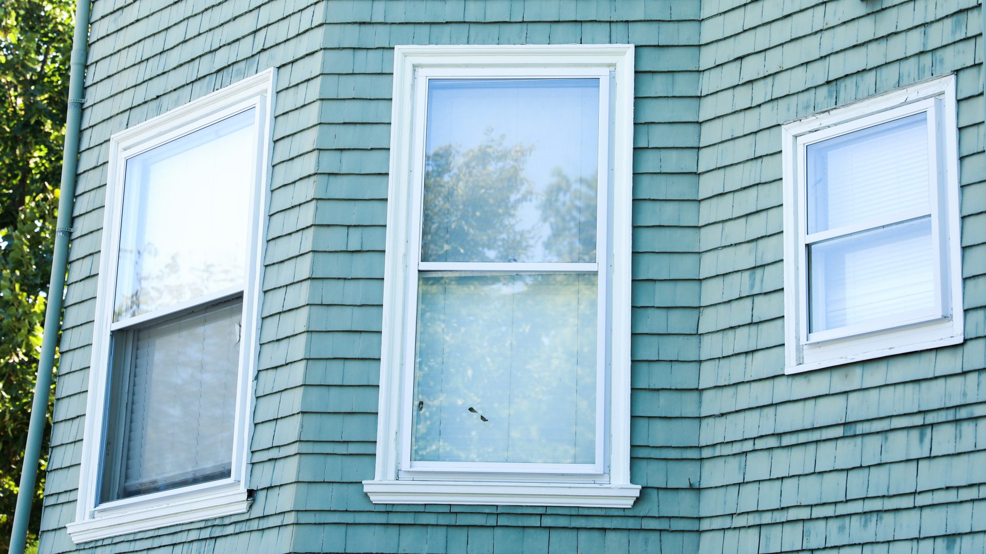 Large vertical windows on home with bright teal siding