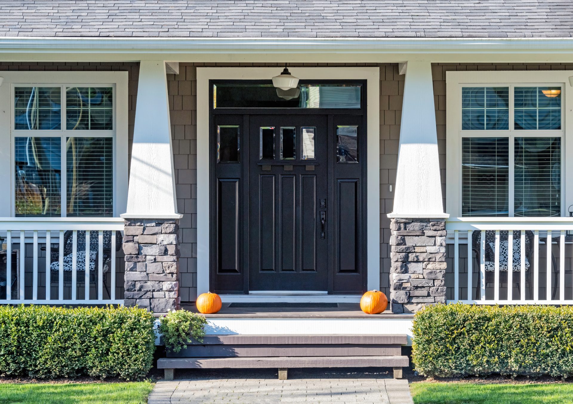 Black door on a stone home with a porch