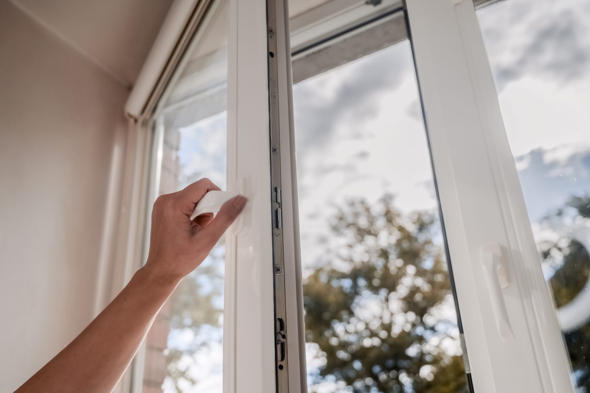 Person opening white vinyl windows in their home