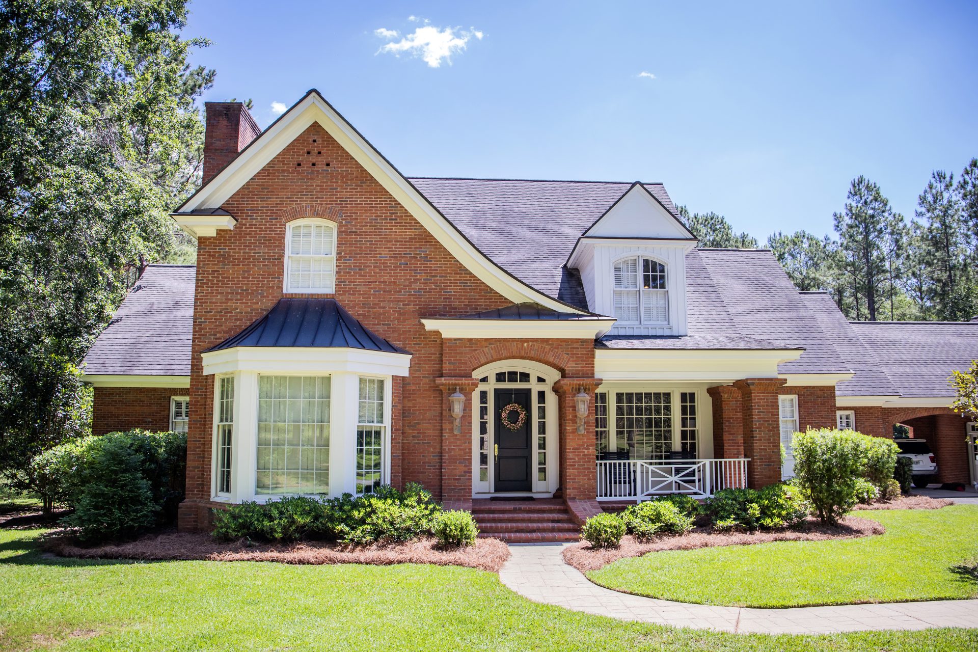 Black door on a brick house with white windows