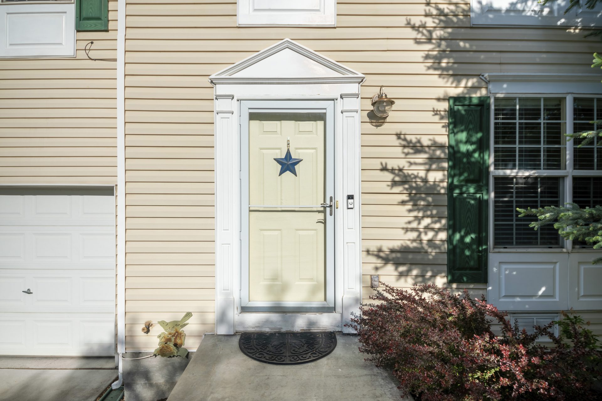Cream colored entry door with white storm door on home in Medicine Hat, AB | GreenFox Windows & Doors