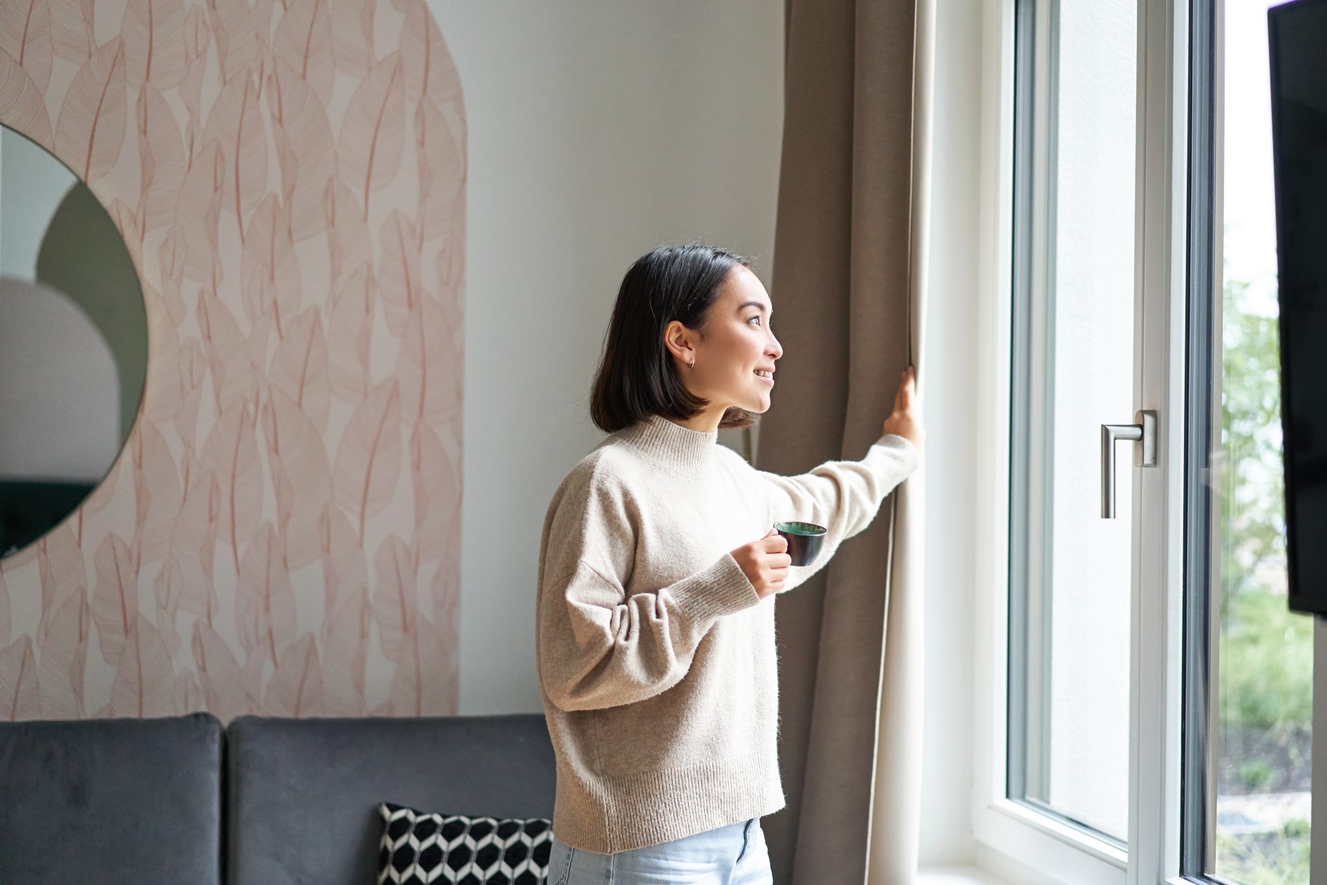 Woman standing in front of window with mug enjoying the view