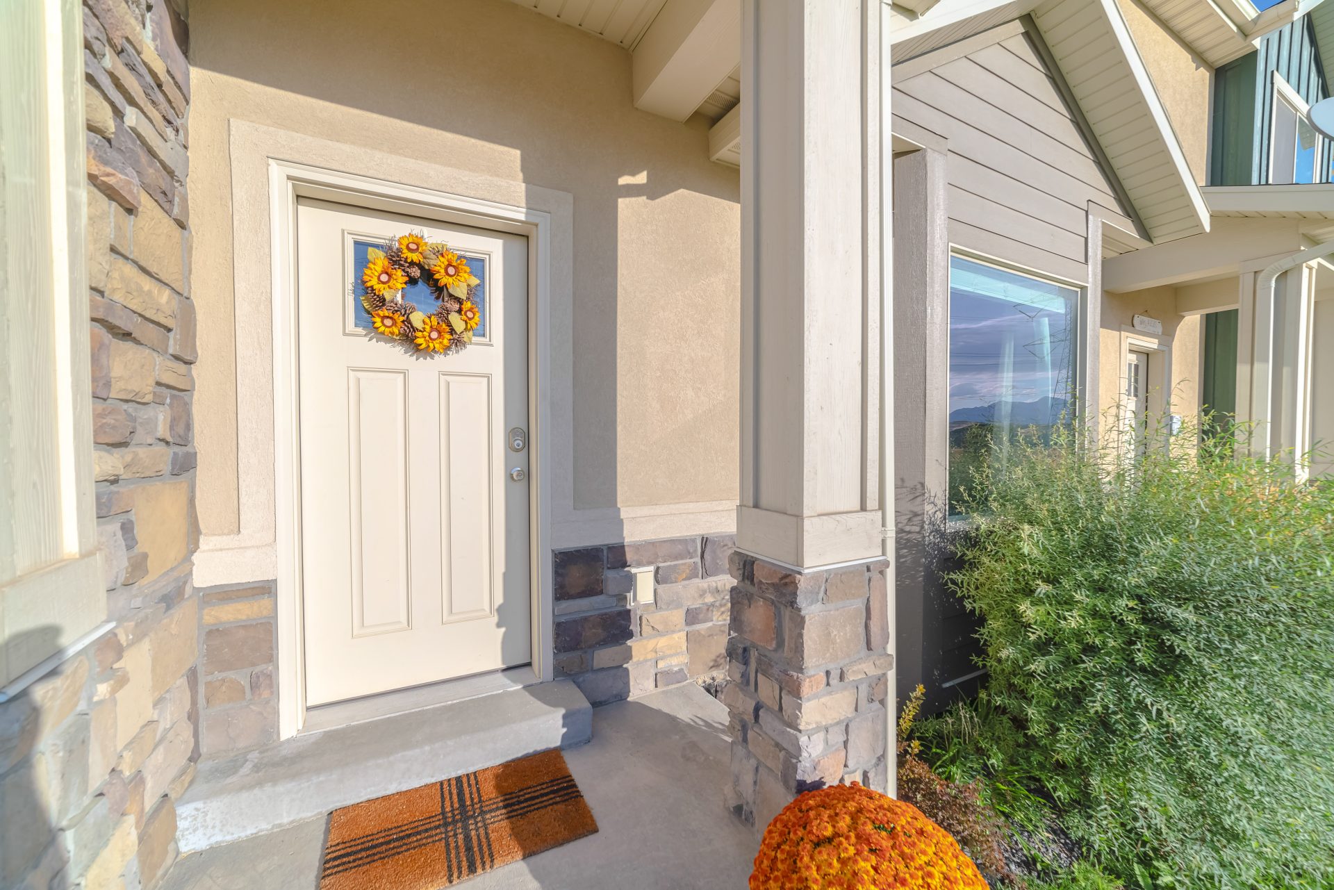 White entry door on home with window covered by an inviting wreath