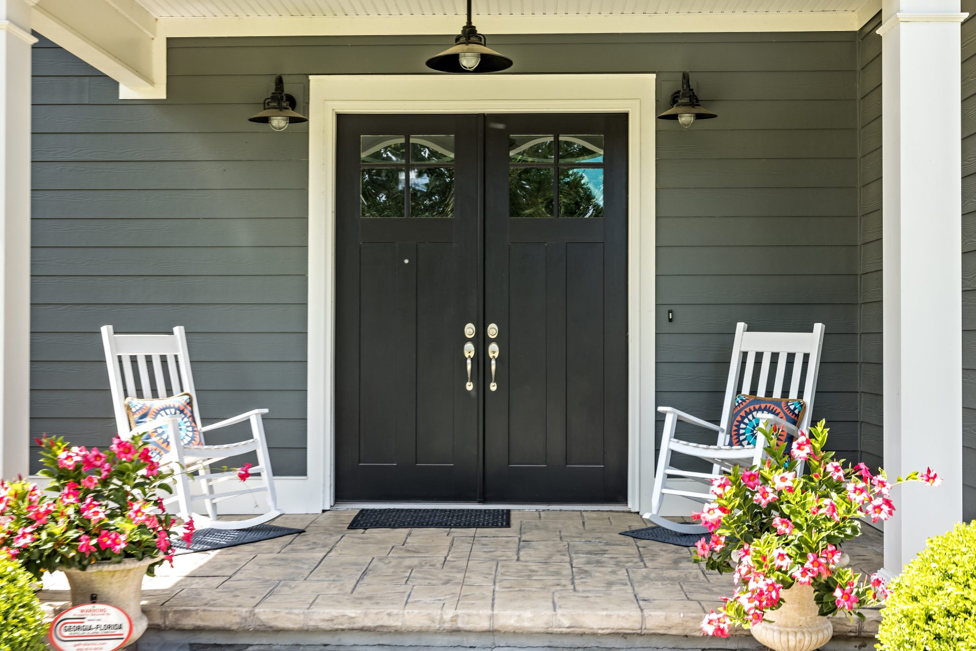 A welcoming front porch featuring a pair of black double entry doors with small glass windows at the top
