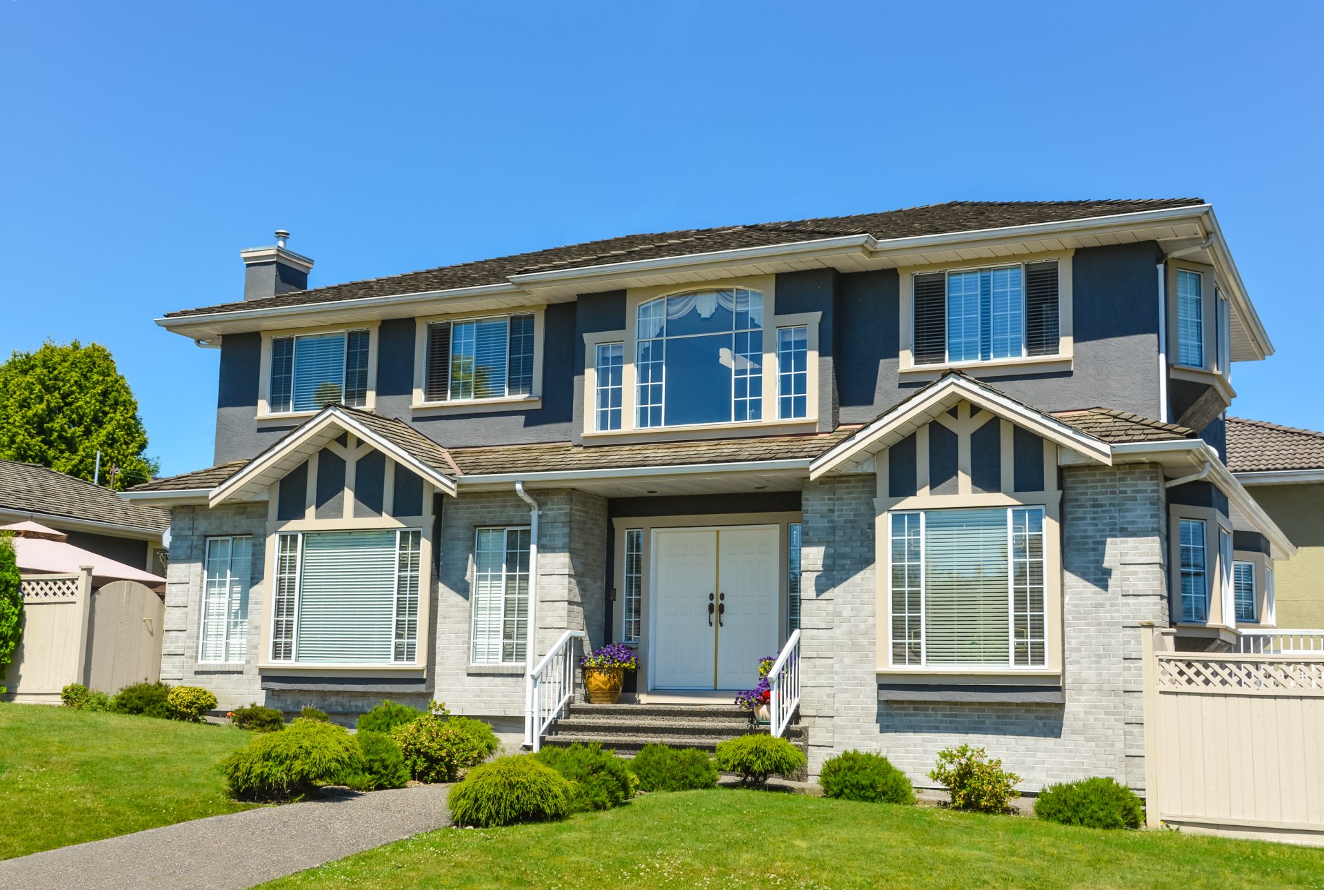 A two-story house with large windows and two white front doors