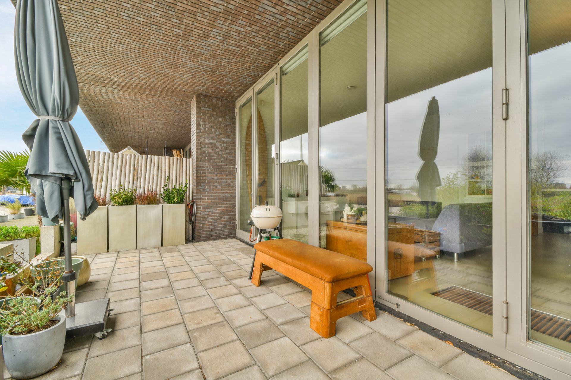 Glass patio doors on the back of a house with cement pavers on the ground.