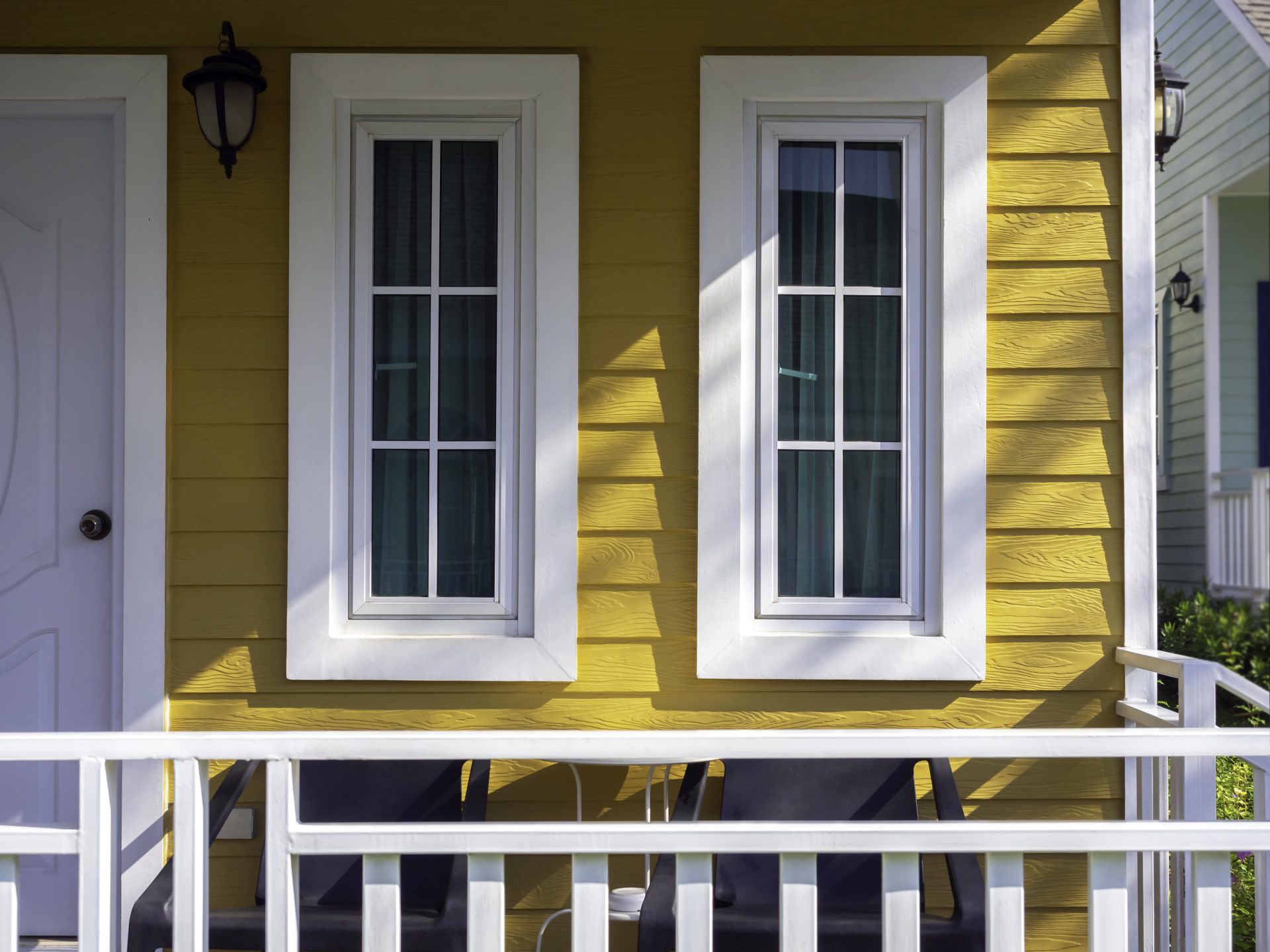 Long and tall white windows on the front porch of a yellow house In Brooks, AB | GreenFox Windows & Doors