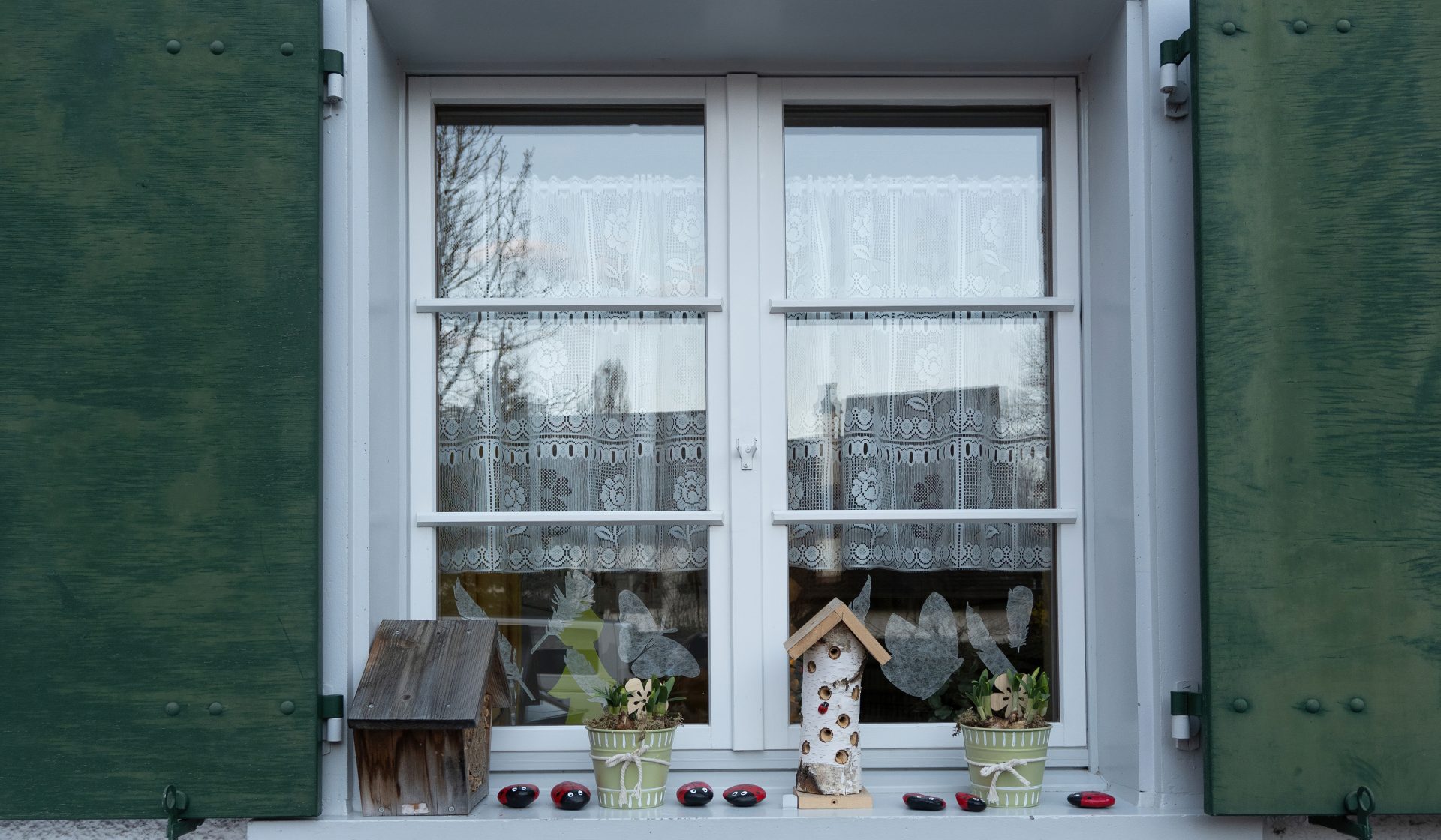 White windows on the side of a house with items on the exterior window sill
