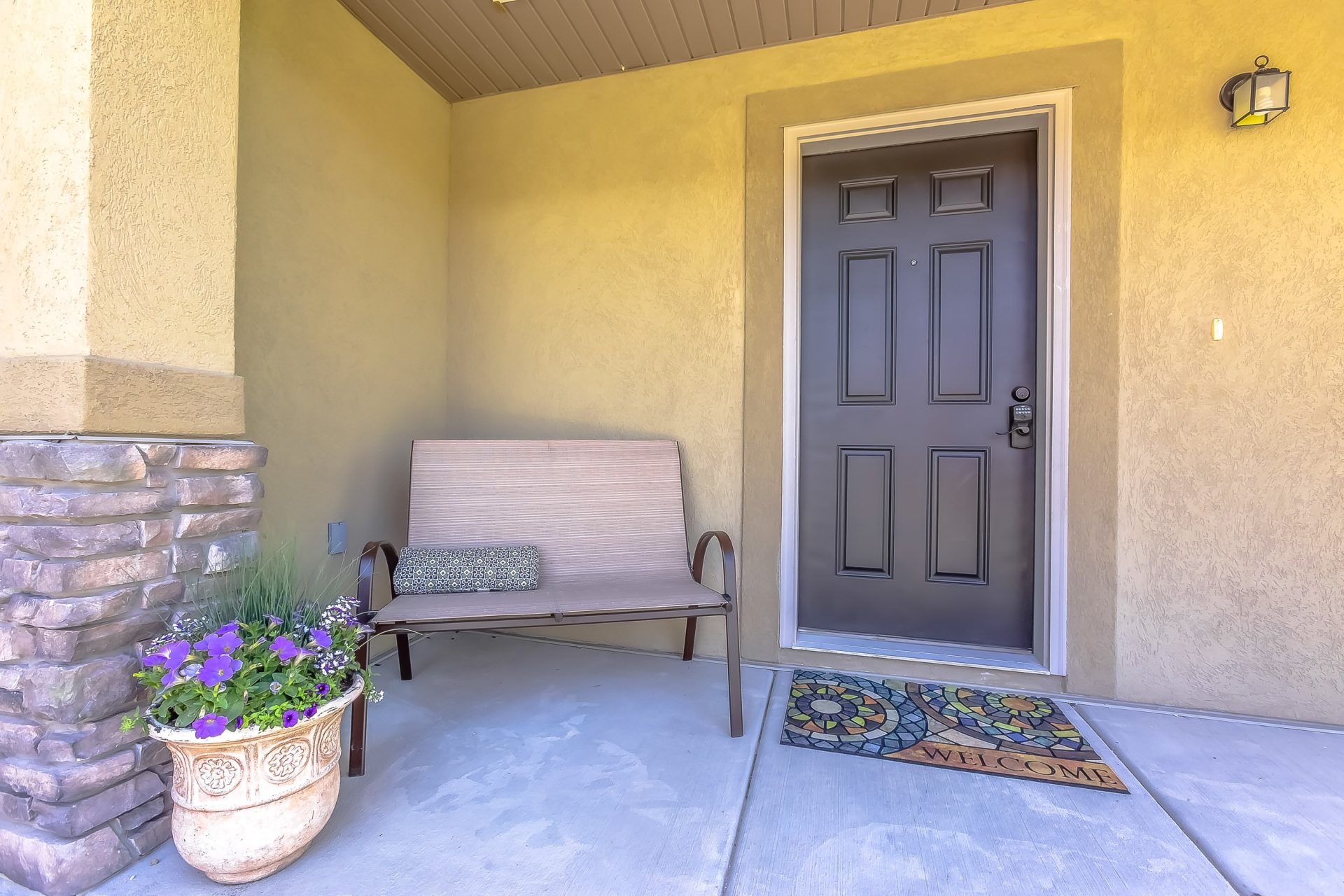 A brown door on a stucco house with a porch swing in the corner