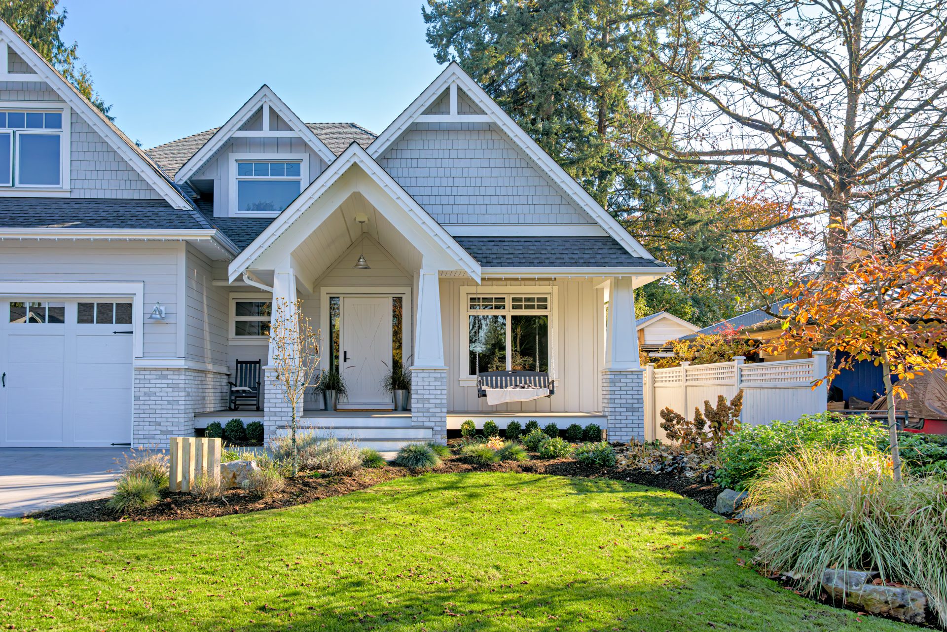 A two-story white house with a white front door, white windows, a white garage door, and an asphalt shingle roof